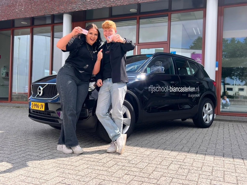Achteraanzicht van de zwarte Volvo lesauto van Rijschool Bianca Sterken op de oprit.